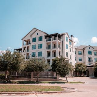 A sunny view of a modern apartment building surrounded by trees.