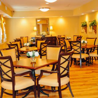 A warmly lit dining room with neatly arranged tables and chairs, featuring tasteful decor.