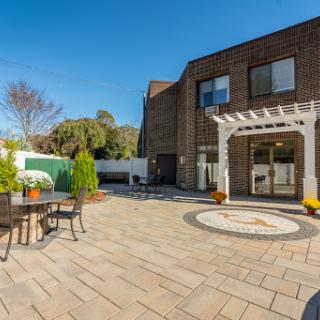 A beautifully designed outdoor patio area featuring a pergola, dining set, and well-maintained landscaping.