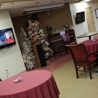 A cozy restaurant interior decorated for the holiday season, featuring a Christmas tree and a television.