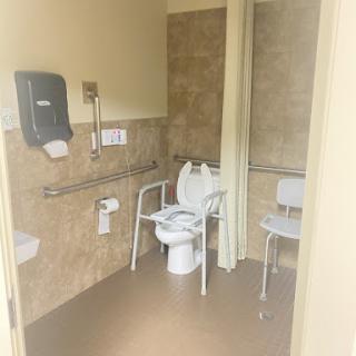 An accessible restroom equipped with support bars and a chair.
