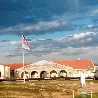 A striking view of a building with a flag in the foreground under a dynamic sky.