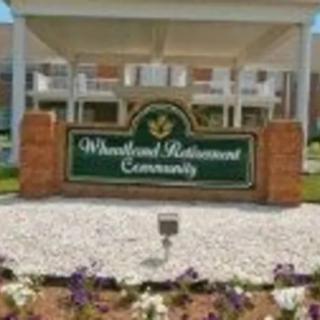 Entrance sign for Woodland Retirement Community surrounded by landscaping.