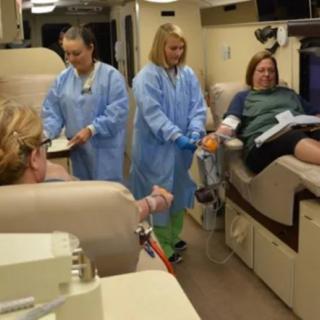 Healthcare professionals assisting a patient during a blood donation procedure.