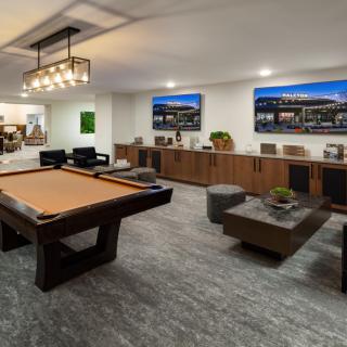 A modern game room featuring a billiards table and comfortable seating with stylish wood accents and artwork on the walls.