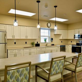 A spacious modern kitchen with a large island, overhead lighting, and contemporary appliances.