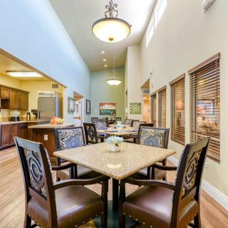A cozy dining area with elegant furniture and warm lighting, adjacent to a modern kitchen.