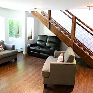 A cozy living room with modern furniture and a wooden staircase.