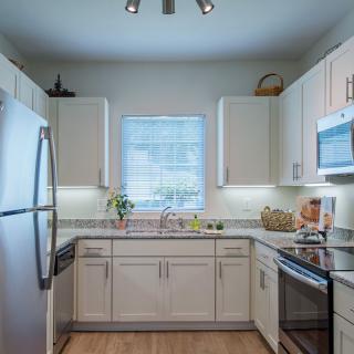 A modern kitchen with sleek white cabinets and stainless steel appliances.