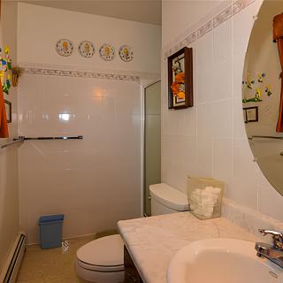 A clean and well-organized bathroom with a sink, mirror, toilet, and walk-in shower.