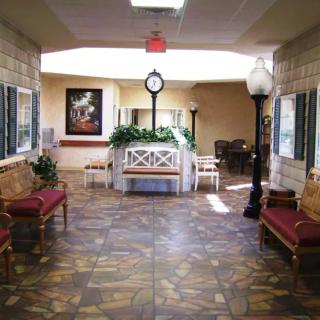 A cozy lobby area featuring benches, a central clock, and decorative plants.