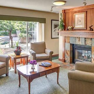 A cozy living room with armchairs, a fireplace, and a coffee table by the window.