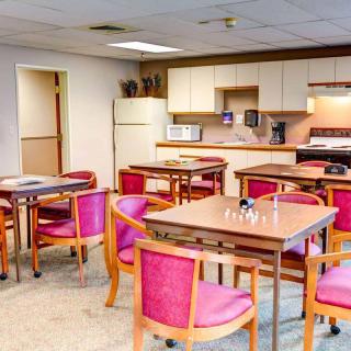 A community room with kitchen facilities, featuring several tables and chairs.