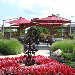 A beautifully landscaped garden with red flowers and large patio umbrellas providing shade over seating areas.