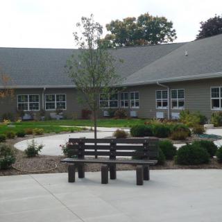 A peaceful courtyard with benches and landscaping in front of a building.