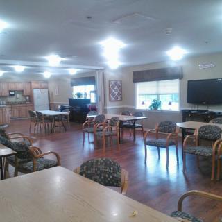 A community room with chairs, tables, and a television.