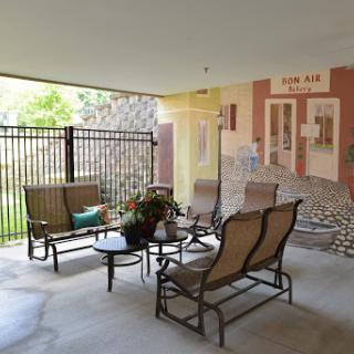 A cozy outdoor seating area featuring comfortable chairs, a table with plants, and a colorful mural in the background.