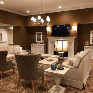 A cozy, elegantly decorated living room featuring comfortable seating, a chandelier, and a warm fireplace.