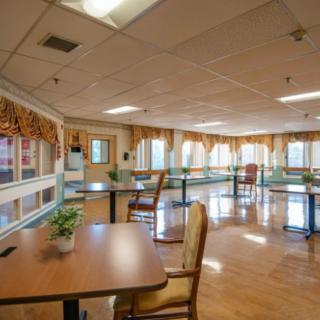A spacious dining area with tables and chairs, surrounded by large windows that allow natural light to flood the room.