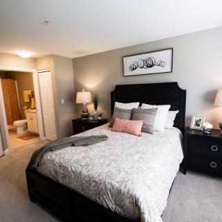 A modern and cozy bedroom with a neatly made bed, nightstands, and warm lighting.