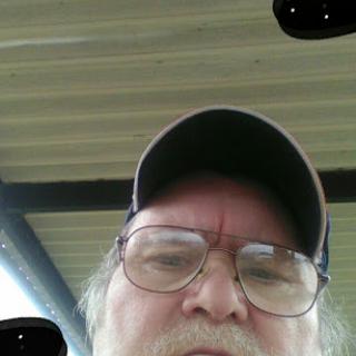 A man taking a selfie outdoors under a shelter.