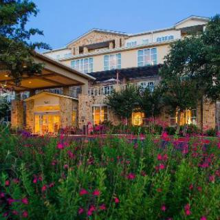 A hotel building with beautifully landscaped gardens blooming with flowers in the evening light.