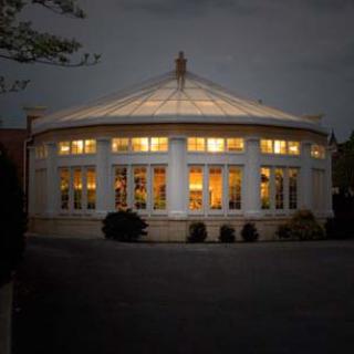 A beautifully illuminated circular building at night, showcasing its elegant architecture and warm interior lights.