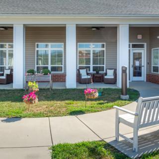 A welcoming porch with benches and flowers in front of a building.