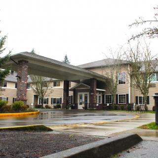 A large building with a covered entrance and surrounding trees on an overcast day.