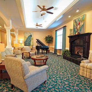 A cozy living room with elegant furniture, a fireplace, and a grand piano.
