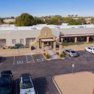 A building with a parking lot and several cars parked in front during the daytime.