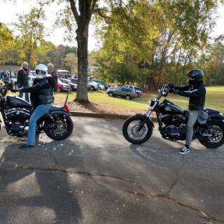 Two bikers taking a break in the park, showcasing their rides.