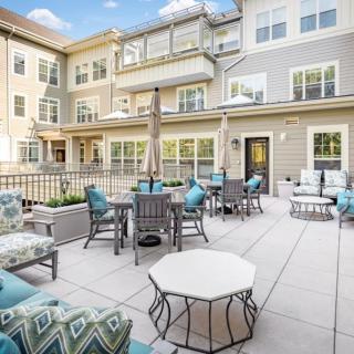 A modern apartment building with a spacious outdoor patio featuring stylish seating and tables.