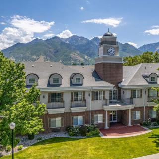A picturesque building set against a backdrop of mountains with a bright sky and lush greenery.