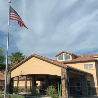 A building with an American flag in front and a cloudy sky above.
