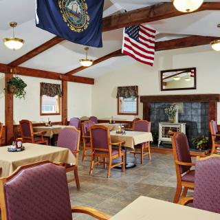 A cozy dining area with multiple tables and chairs, adorned with American and state flags.