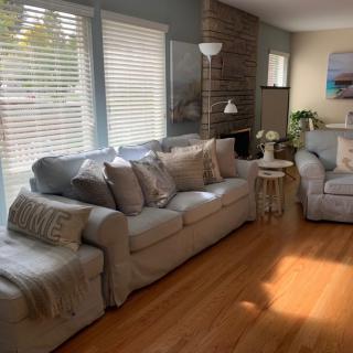 A cozy living room with a large sofa, wooden floors, and ample natural light.