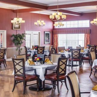 An elegant dining room setup with neatly arranged tables and chairs, featuring warm lighting and tasteful decor.