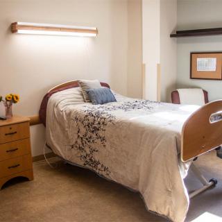 A clean and neatly arranged hospital room with a bed and furniture.