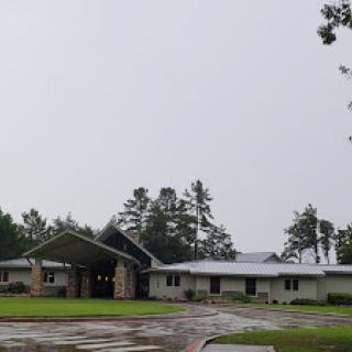 A modern building set in a rainy landscape, surrounded by trees.