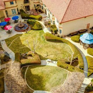 Aerial view of a landscaped courtyard with pathways, patio furniture, and colorful umbrellas.