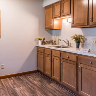 A modern kitchen with wooden cabinets and sleek countertops, featuring homey decor.