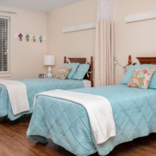 A cozy bedroom featuring two twin beds with light blue bedding and decorative pillows, set against a soft, neutral backdrop.