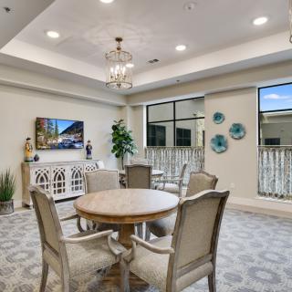 A stylish dining area with elegant decor and a round table, illuminated by a chandelier.