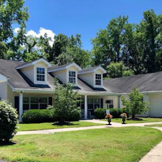 A charming single-story house surrounded by lush greenery and a well-maintained lawn.