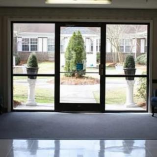 View from inside a building looking out through glass doors towards a courtyard with plants.