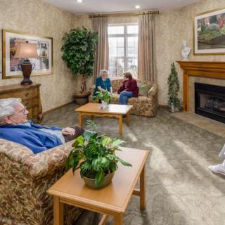 A cozy living room with seniors engaging in conversation by the fireplace.