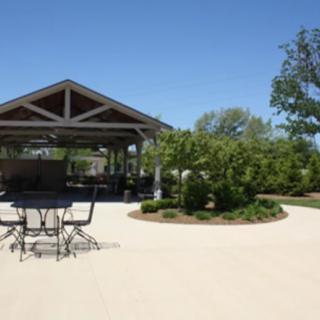 A pavilion with outdoor seating in a landscaped park on a sunny day.