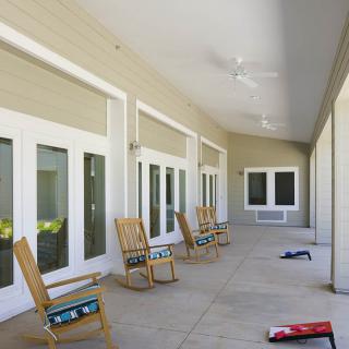 A spacious porch with several rocking chairs offers a serene outdoor seating area.
