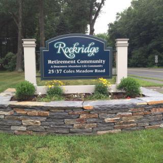 A sign for Rockridge Retirement Community set on a landscaped stone wall.